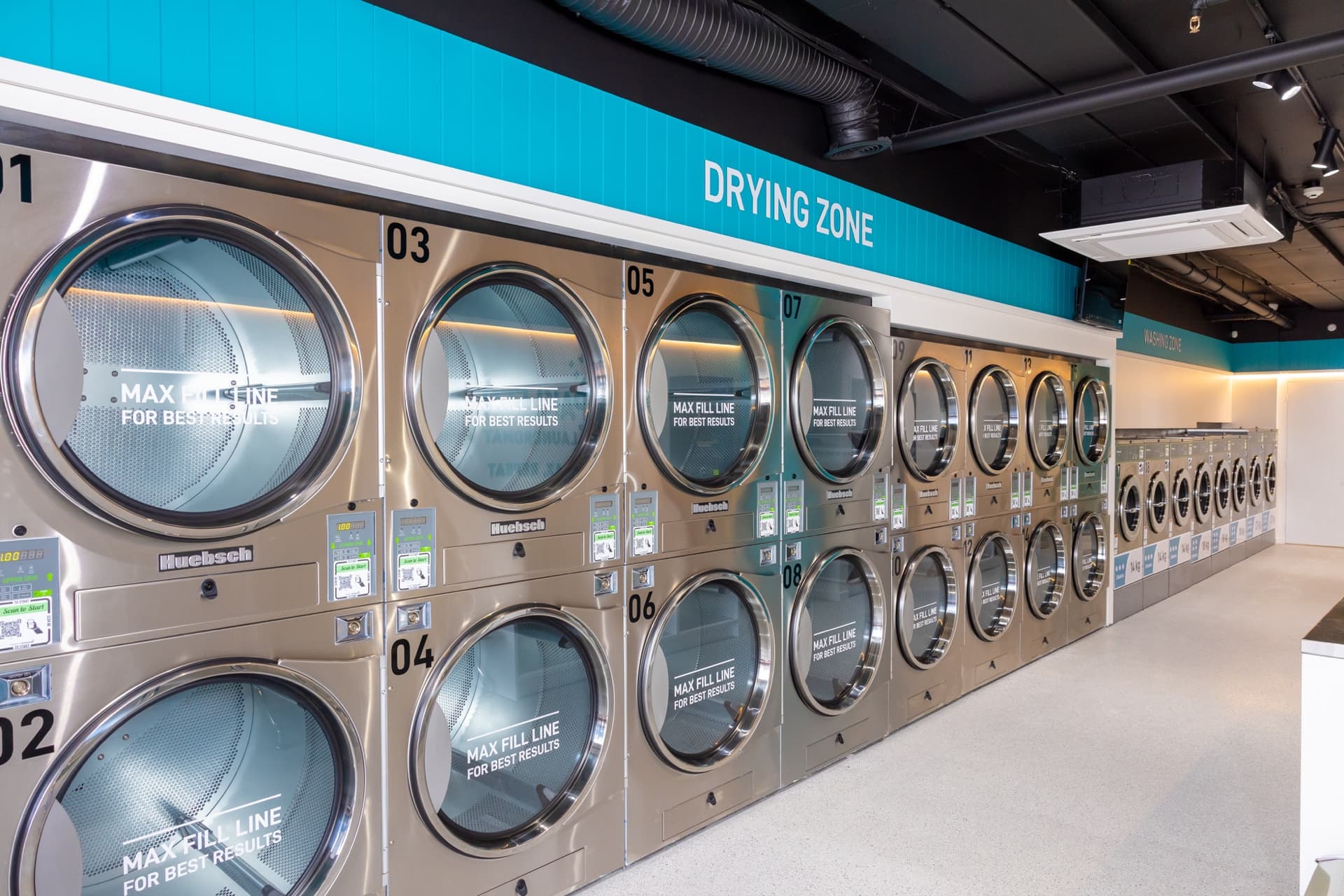 The Spakleen drying zone: a long double bank of numbered jumbo dryers with max fill line markings running the length of the store
